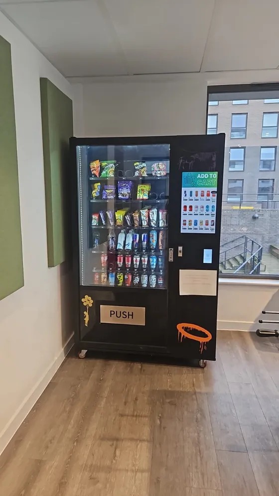 Black snack and drink vending machine in a staff area