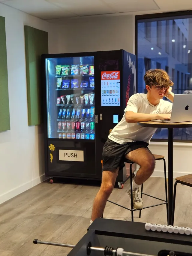 Gym member sitting beside a rented snack and drink vending machine