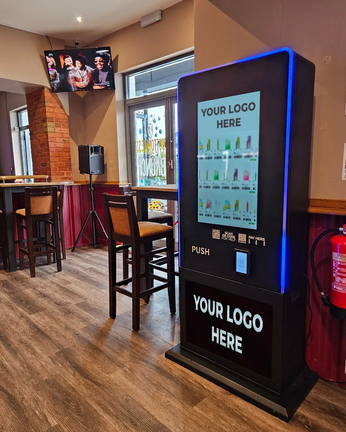 JV180 freestanding touchscreen lifestyle vending machine in a pub, with blue LED edge lighting and space for your own logo