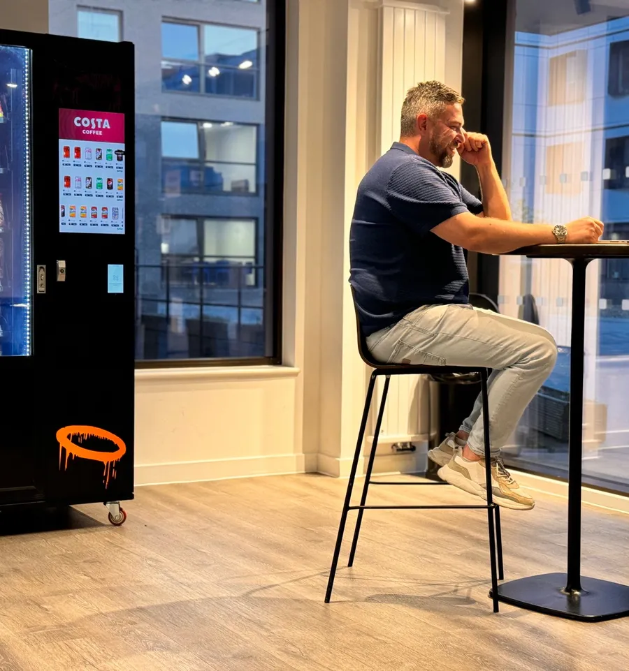 Man relaxing beside the vending machine in the Rhodaus Court lounge