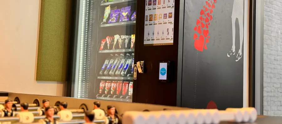 Custom-wrapped snack and drink machine next to the foosball table