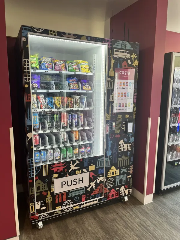 Travel-themed wrapped snack and drink machine with a Costa Coffee touchscreen menu